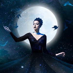 A woman dressed in black stands in front of a full moon surrounded by birds