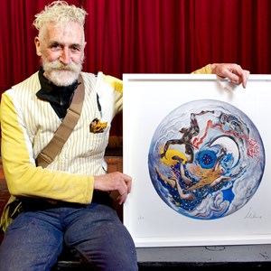 John Byrne posing with a replica of his design in a white frame