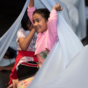 An Indian young girl dancing with some fabrics