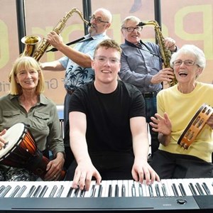 Musician Gus Harrower plays instruments with Tea and Jam attendees