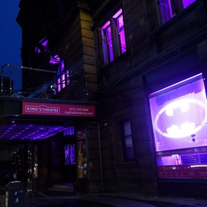 The King's Theatre lit in purple with the bat signal projected on a window