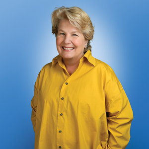 Sandi in a yellow shirt against a blue background