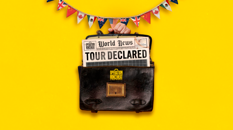 A hand holds a briefcase with a newspaper reading "Tour Declared" sticking out, against a yellow background with international flag bunting above.